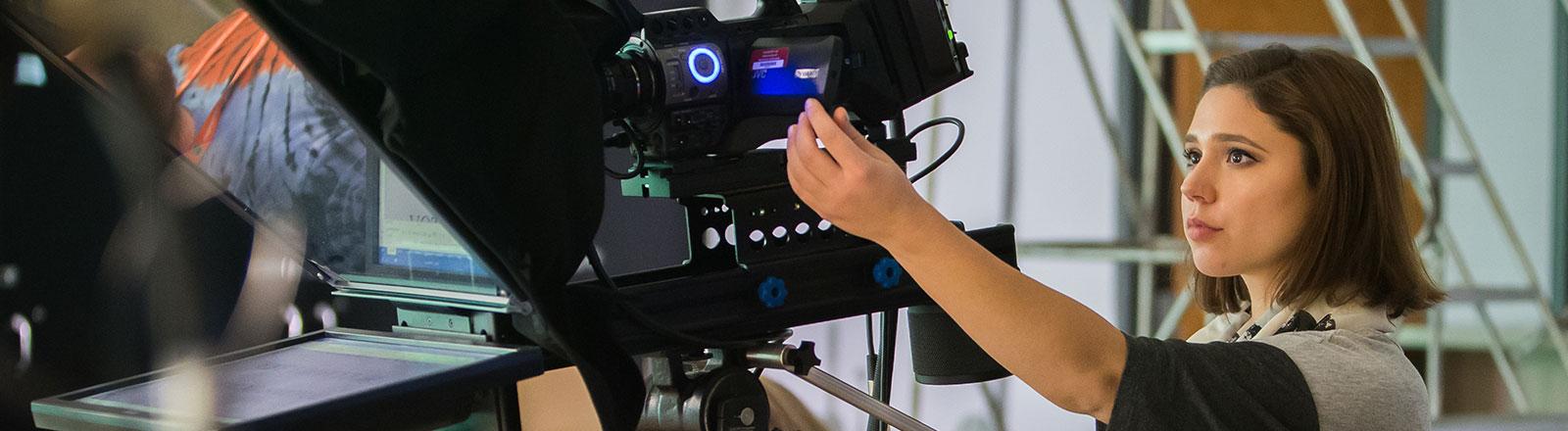 Journalism student adjusting camera in video studio