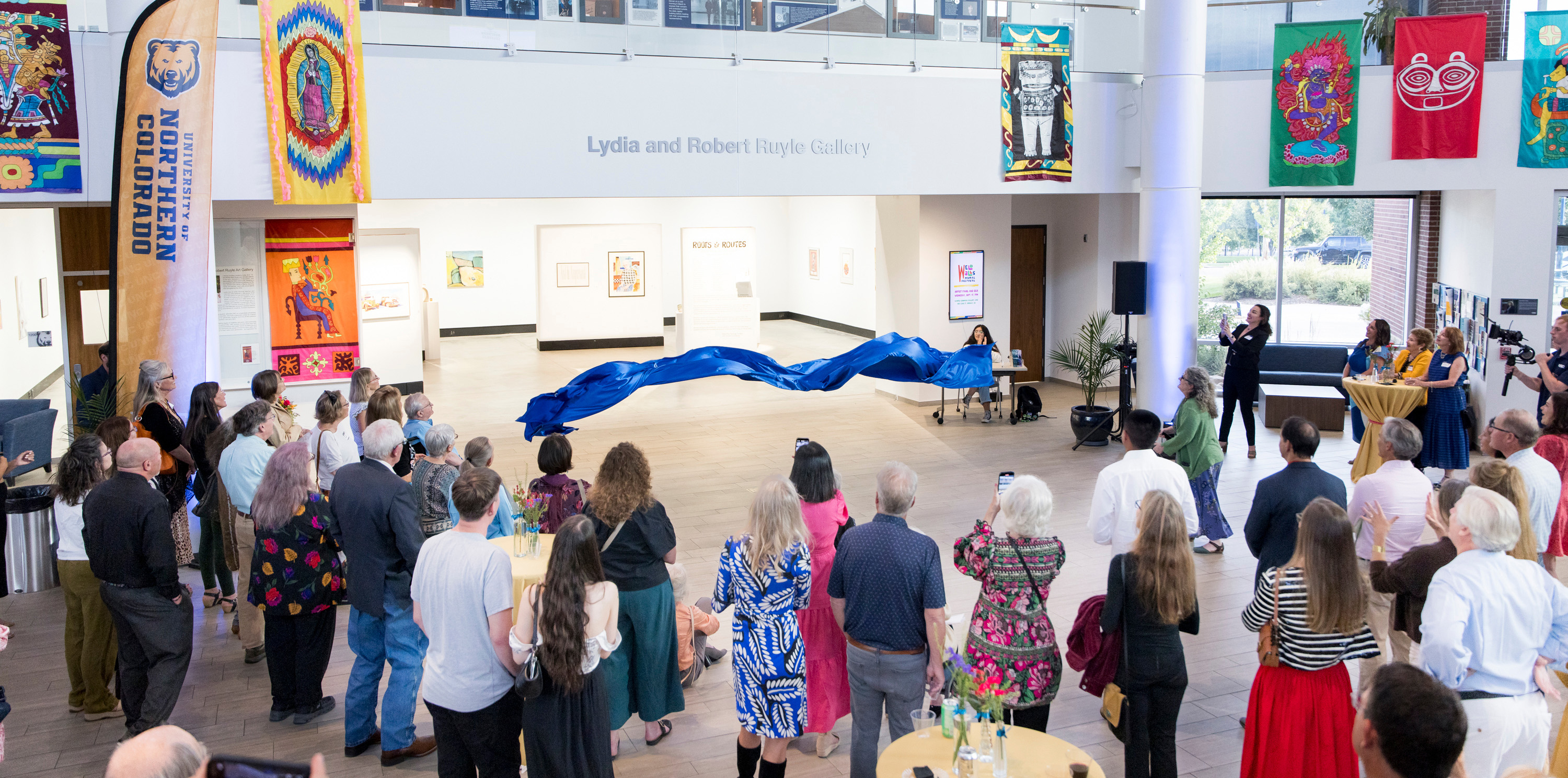 A banner dropping from the title of a gallery with a group watching