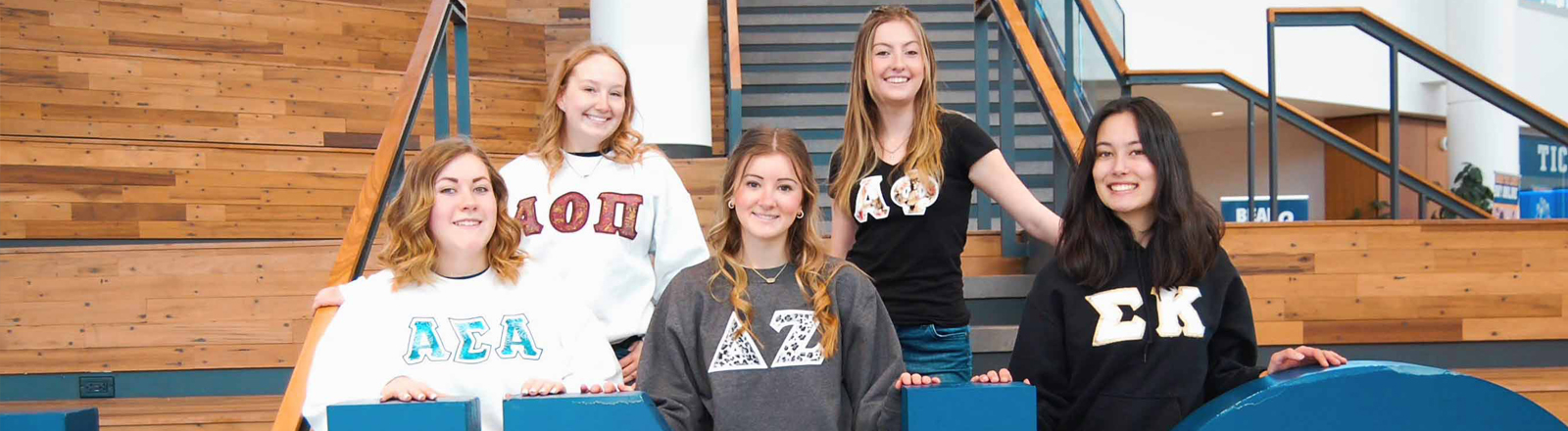 A group of NPC sorority women pose on a set of bleachers.