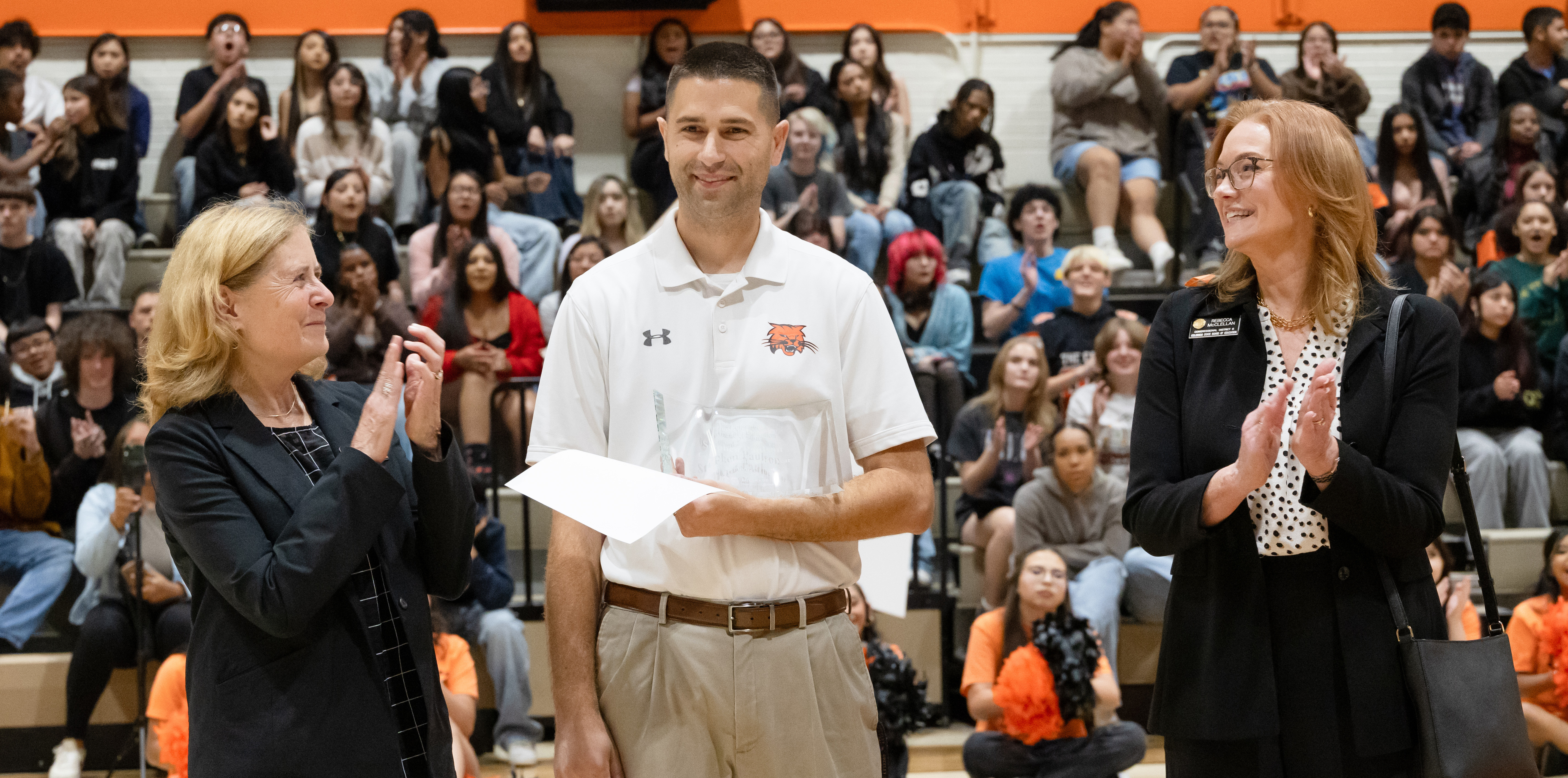 Stephen Paulson standing between two women holding an award piece of paper