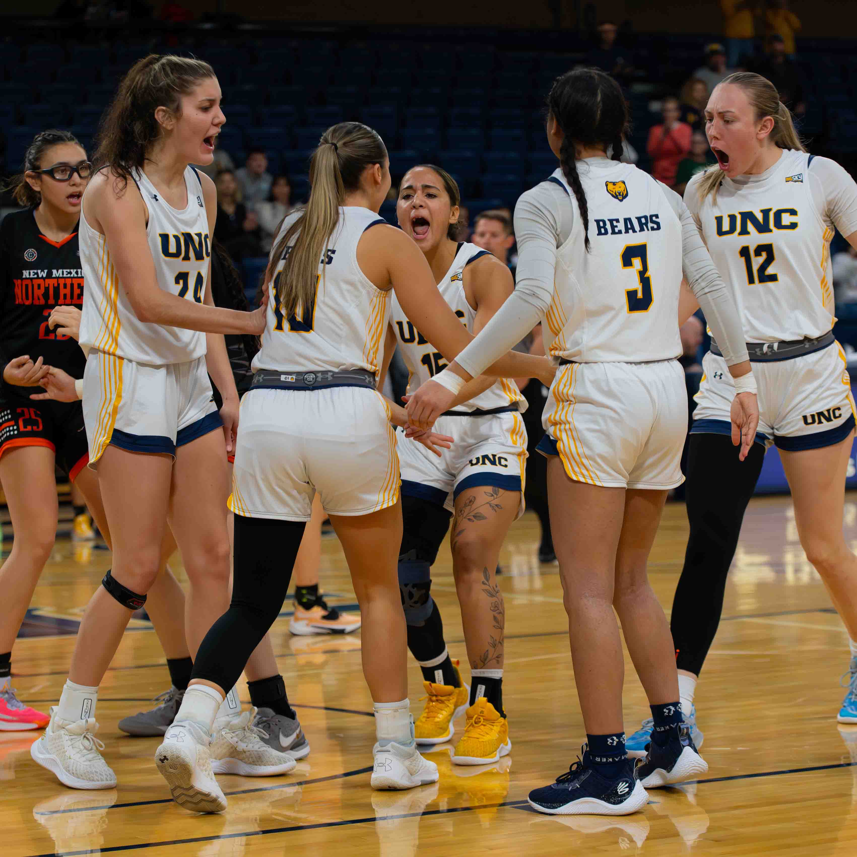 Women's basketball players celebrate on the court during a game.